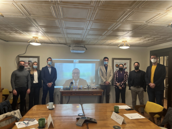 Group of people posing for photo in front of projected photo of a man