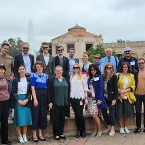 A group of 18 professionals, representing IVLP participants and representatives from SANDAG are pictured outside in front of a fountain and science center.