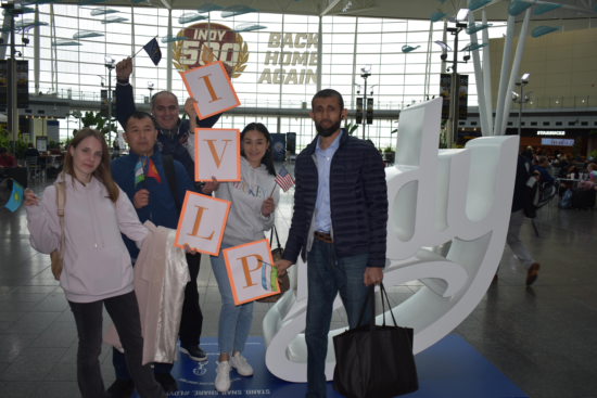 Group holding up letters to form IVLP in front of Indy sign.