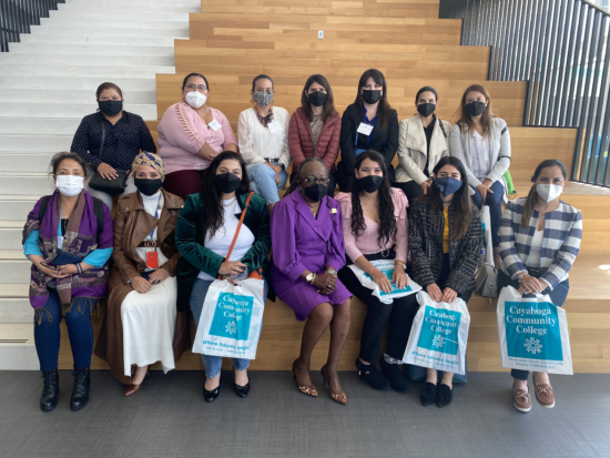 Group of masked women sitting on steps and smiling for photo.