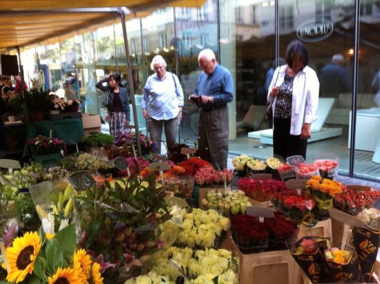 Flowers at a street market with people shopping