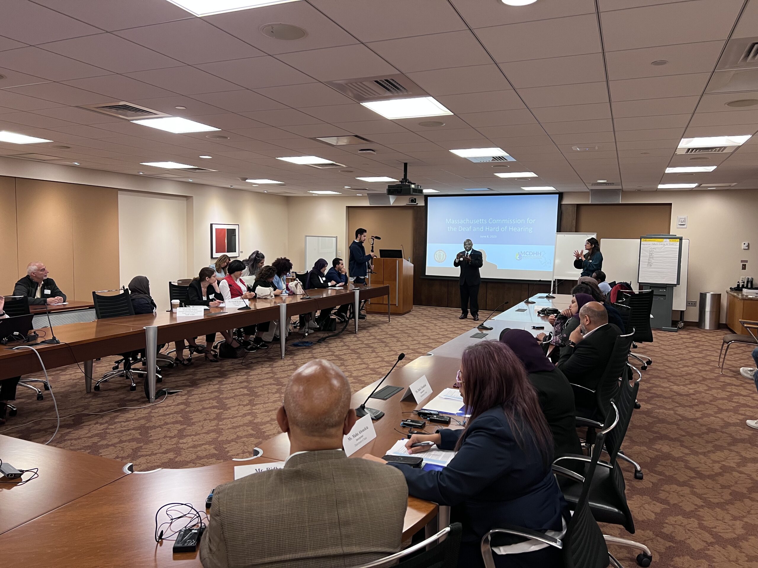 Twenty people attending presentation in business boardroom.