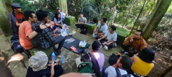Group of young people sit in a circle on outdoor meeting space. 