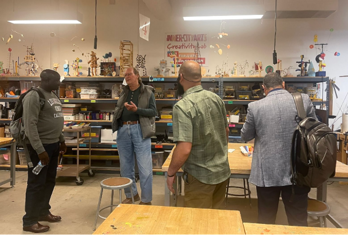 Picture of four people mid-conversation in an art classroom.