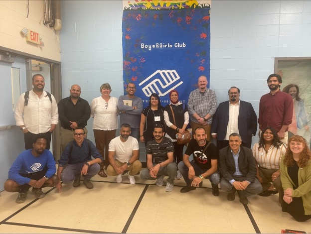 Twenty people pose for picture in front of a Boys & Girls club banner,