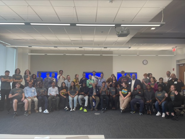 Large group of people pose for picture in large classroom.