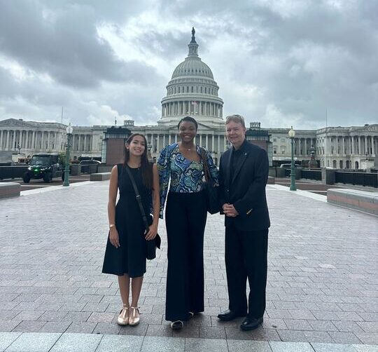 Sofia, Eloah, and John standing and smiling in front of U.S. Capitol Building. 