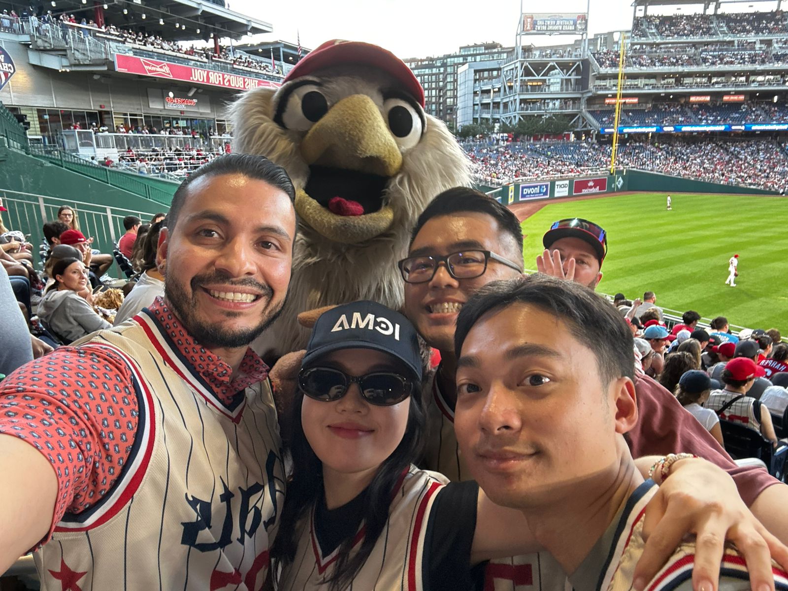 Group of four people poses for a picture with a mascot at a professional baseball game.